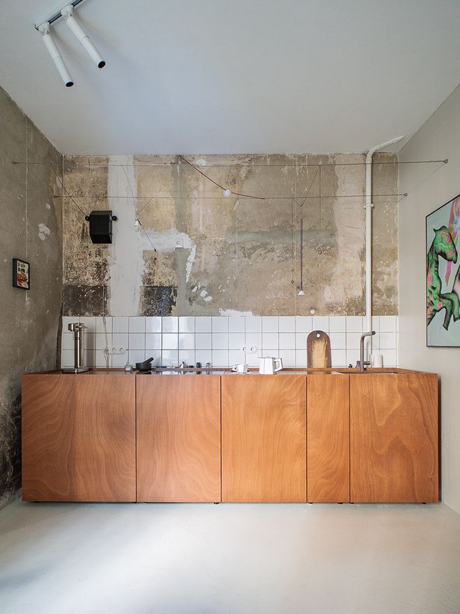A corner of the kitchen where the original plaster wall has been left raw next to wood cabinetry and white tile