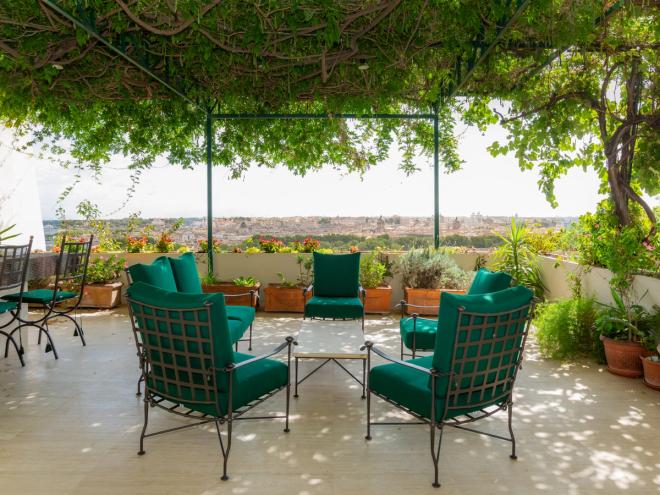 Villa Lante’s green-roofed terrace with outdoor furniture cushioned with green seat pads