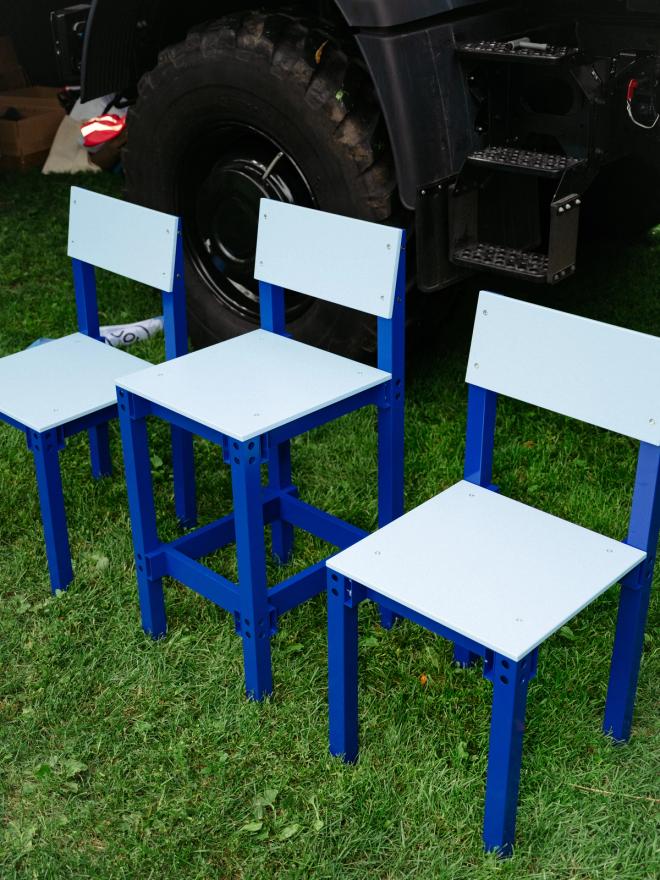 Three blue chairs of different heights arranged in a podium formation on the grass