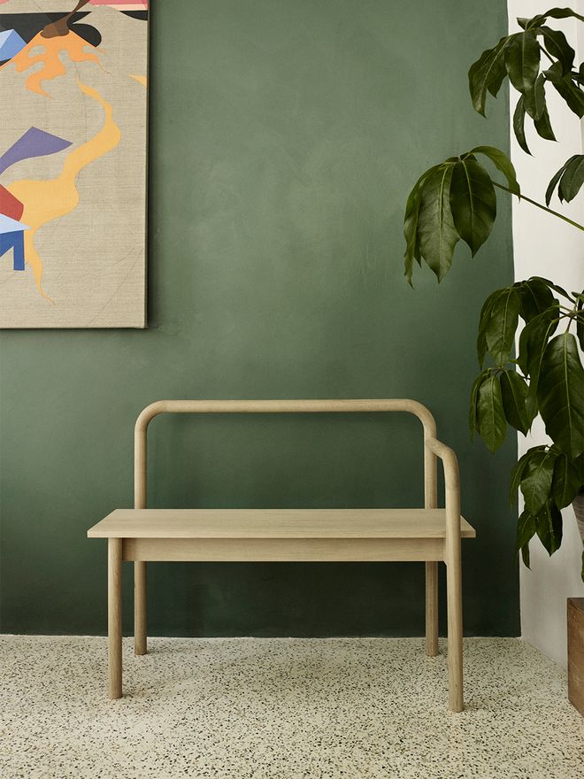 An image of Skagerak's Maissi bench against a dark green wall, as part of the living room decor.