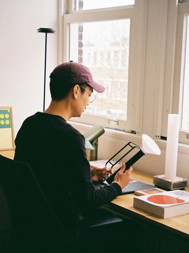 An image of designer Tom Chung sitting beside their work desk.