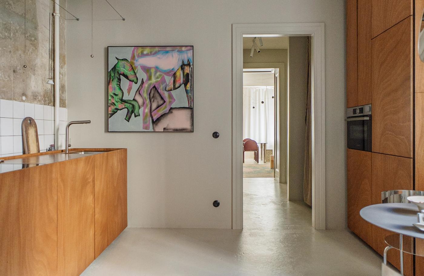 The couple's DIY kitchen in Berlin, with warm wood cabinetry, a concrete floor, and a white tiled backsplash