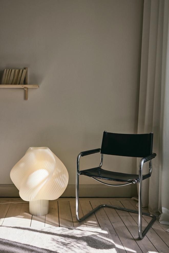 Oversized Soft Serve floor lamp placed on the floor next to a chair 