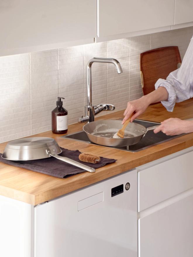 Kuva, jossa paistinpannua pestään käsin.