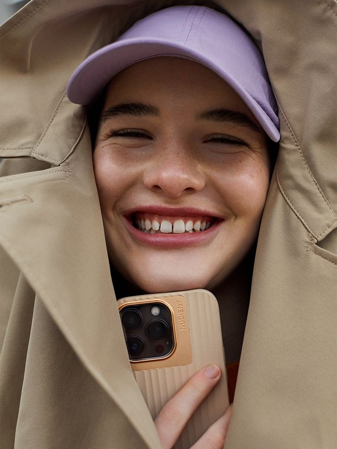 An image of a smiling person holding an iPhone with a Nudient Bold case.