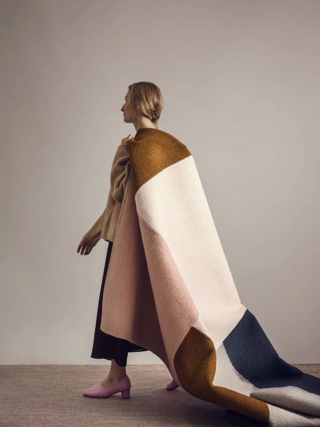 A woman carrying Finarte’s Kortteli wool rug on her shoulder