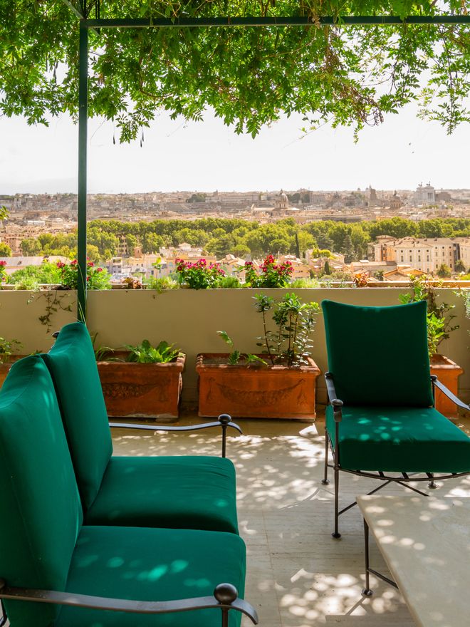 Outdoor furniture with green cushions and a view over central Rome
