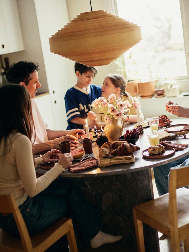 A family gathered around a dining table, Vaarnii Hans pendant above the table
