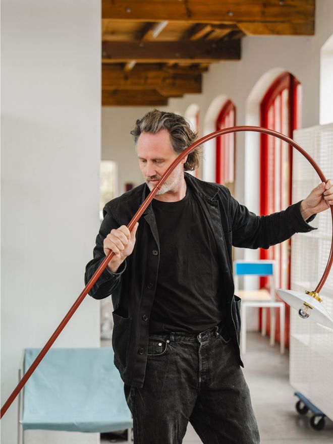 Hannes Van Severen holding a red Hanging Lamp