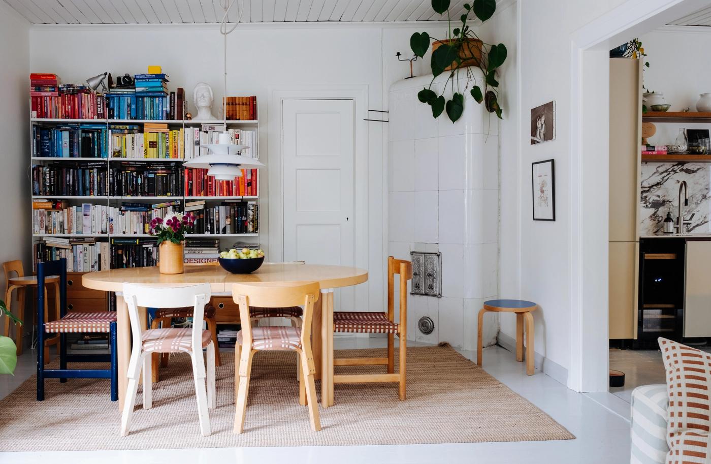 An Artek dining table with HL2 sleeve legs, a PH 5 pendant above it and a bookshelf in the background
