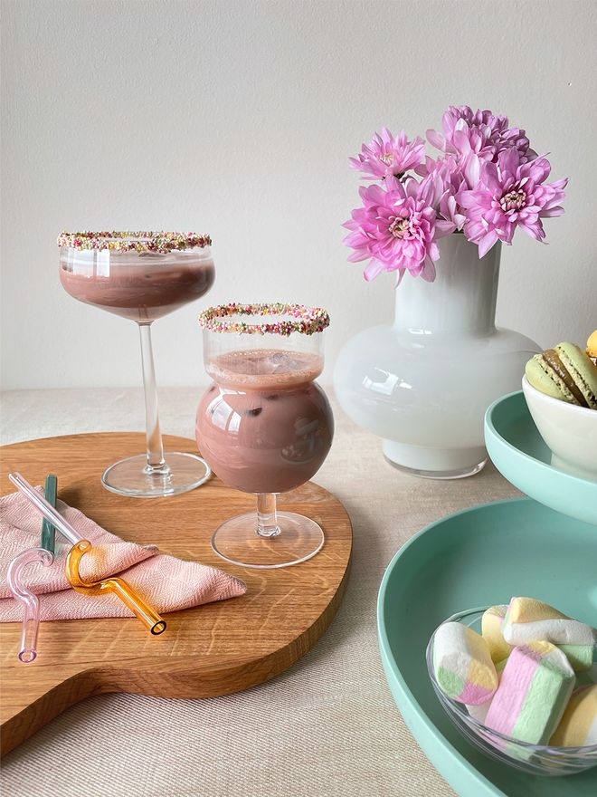 An image of Vitra's Rotary tray, Iittala's Essence glass, Karakter's Sferico No.3 glass and HAY's spiral glass straws in a table setting.