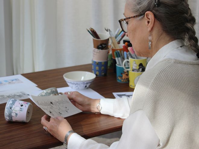 Muumi-kuvittaja Tove Slotte kädessään luonnos talven 2022 Muumi-kuvituksesta