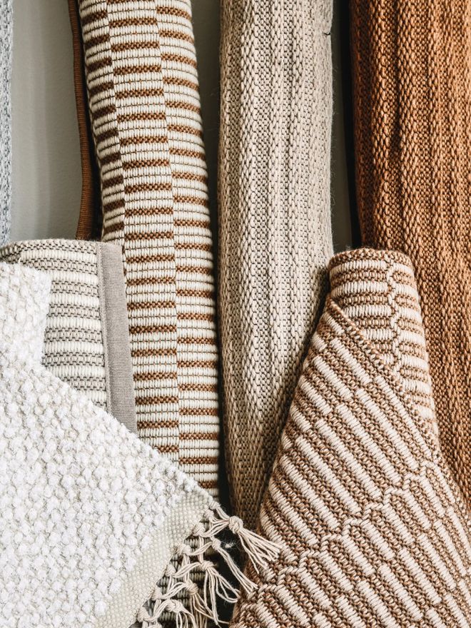 Rolled-up wool rugs from VM Carpet’s Duo collection leaning against a wall