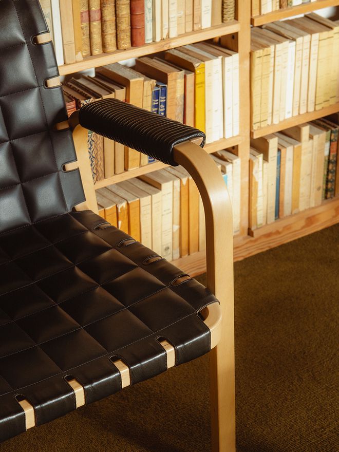 The library room at Villa Skeppet with a leather-upholstered Artek Armchair 45 and floor-to-ceiling wooden bookshelves