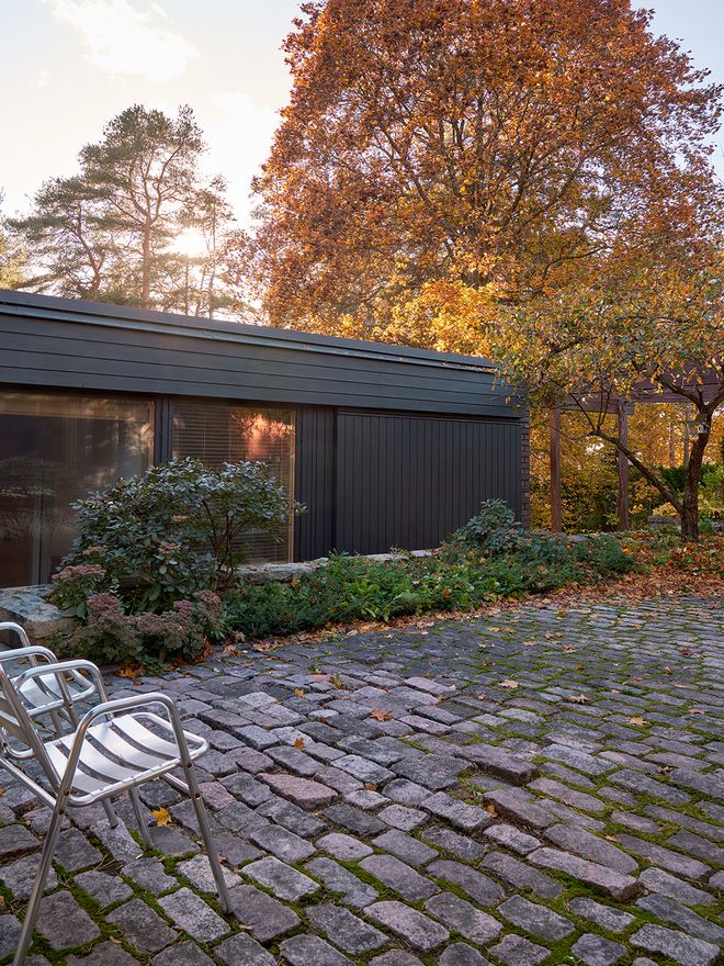 A exterior of a black brick house with an atrium yard