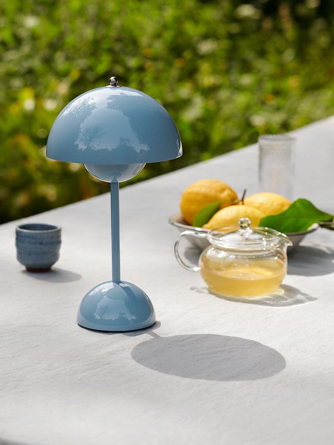 An image of &Tradition's Flowerpot VP9 table lamp in a light blue hue, as part of a summery table setting.