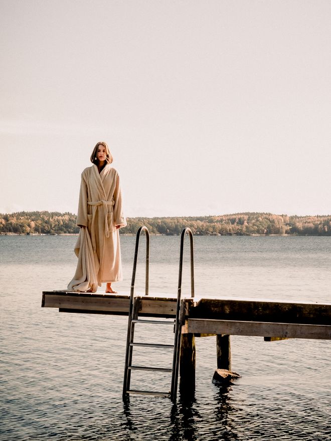 Person standing on the dock wearing long, off-white bathrobe