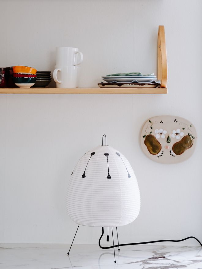 An Akari 1AD table lamp in the kitchen, with a ceramic work by Armi Teva on the wall