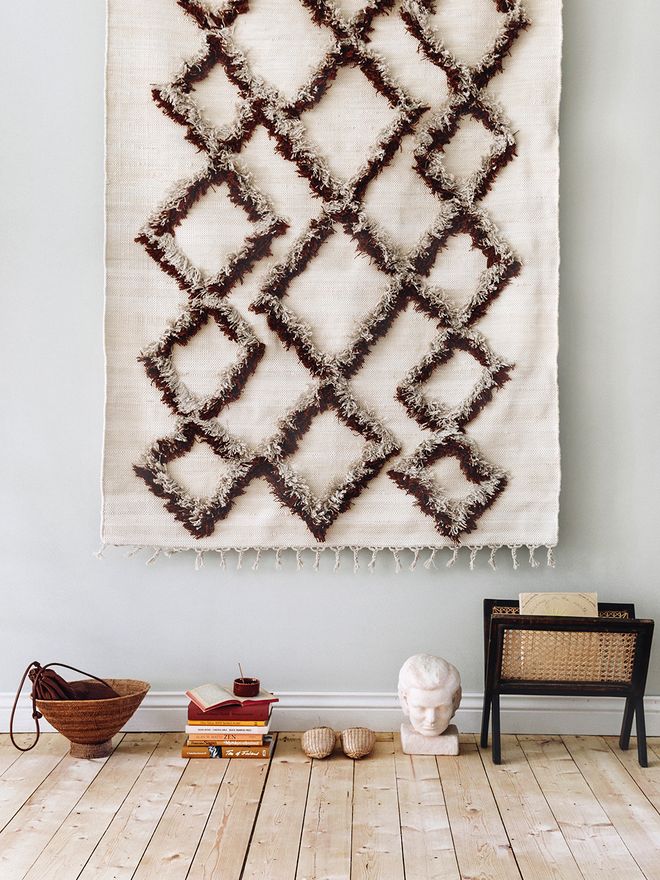 Finarte's Tie rug in brown, hung on the wall.