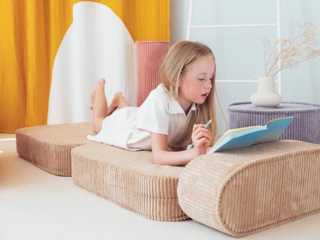 A girl lounging with a notebook on Wigiwama’s beige Flip chair