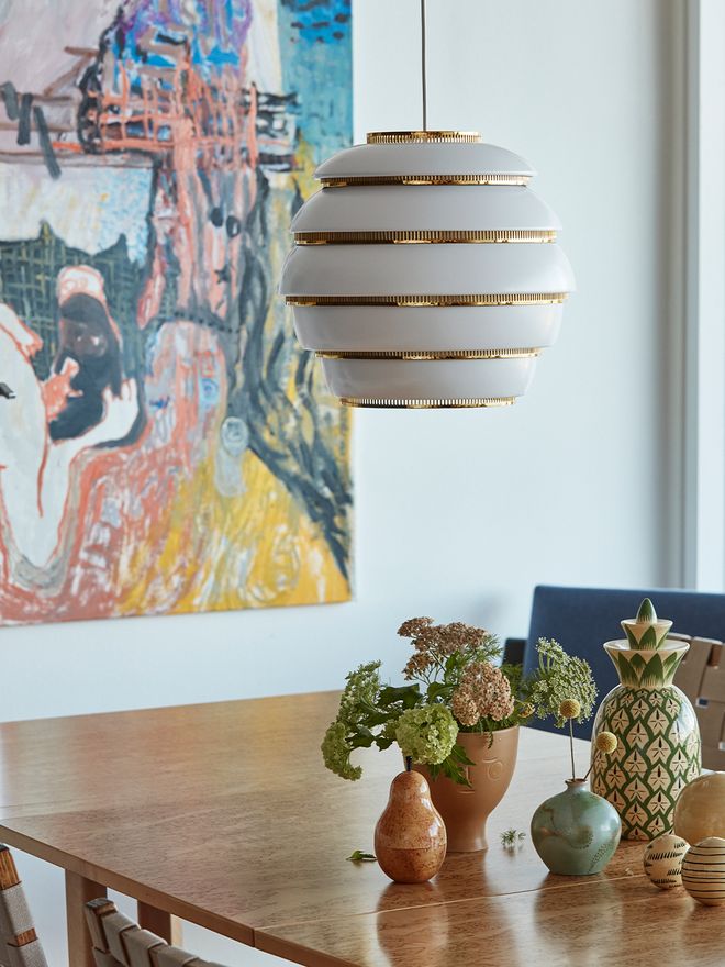 Artek's A331 pendant in brass and white, hung over a kitchen table.
