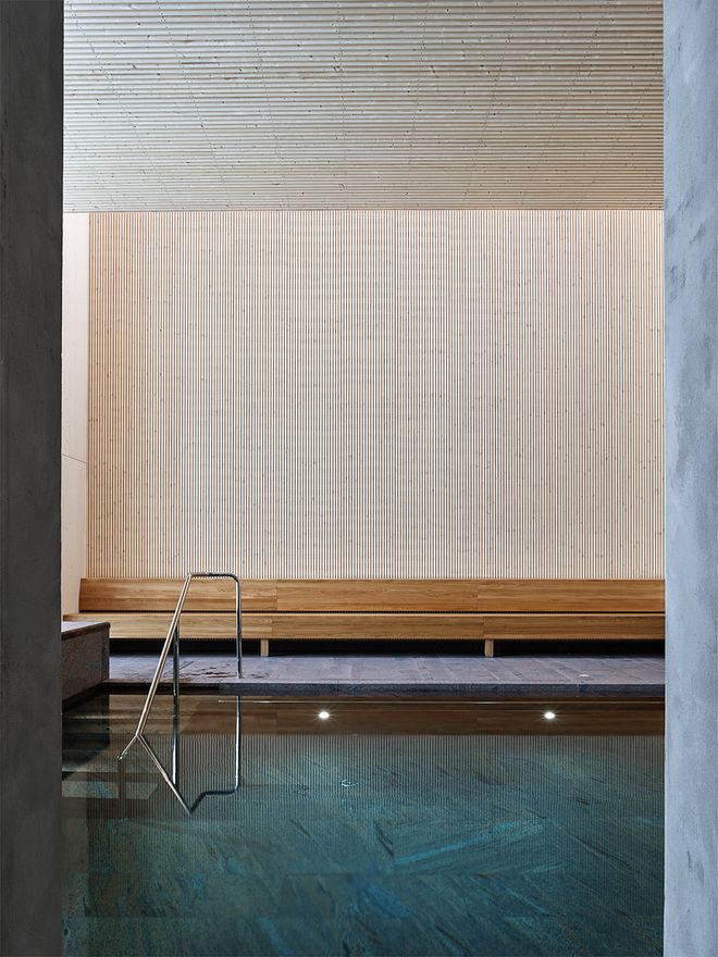 An image of Andrum spa's interior: wooden walls, a stone pool and wooden benches.