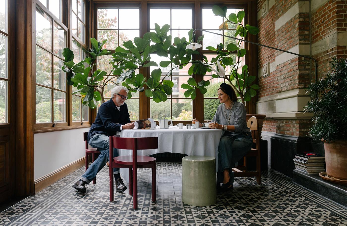 Axel ja Marie istuvat pyöreän pöydän ääressä huoneessa, jossa on isot ikkunat ja kaakelilattia