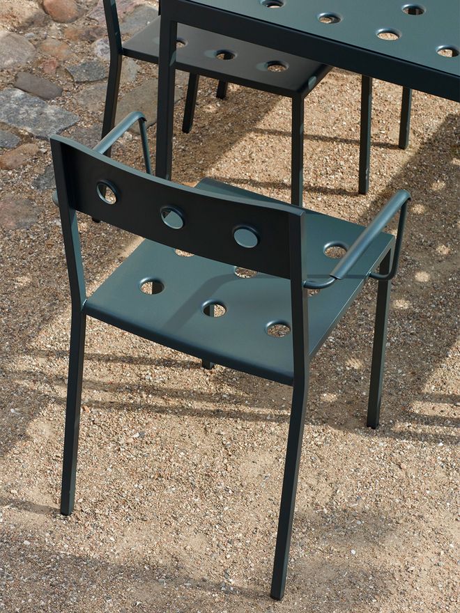 HAY’s green Balcony chair has three holes in the back and a total of nine holes in the seat. The chair also has armrests.