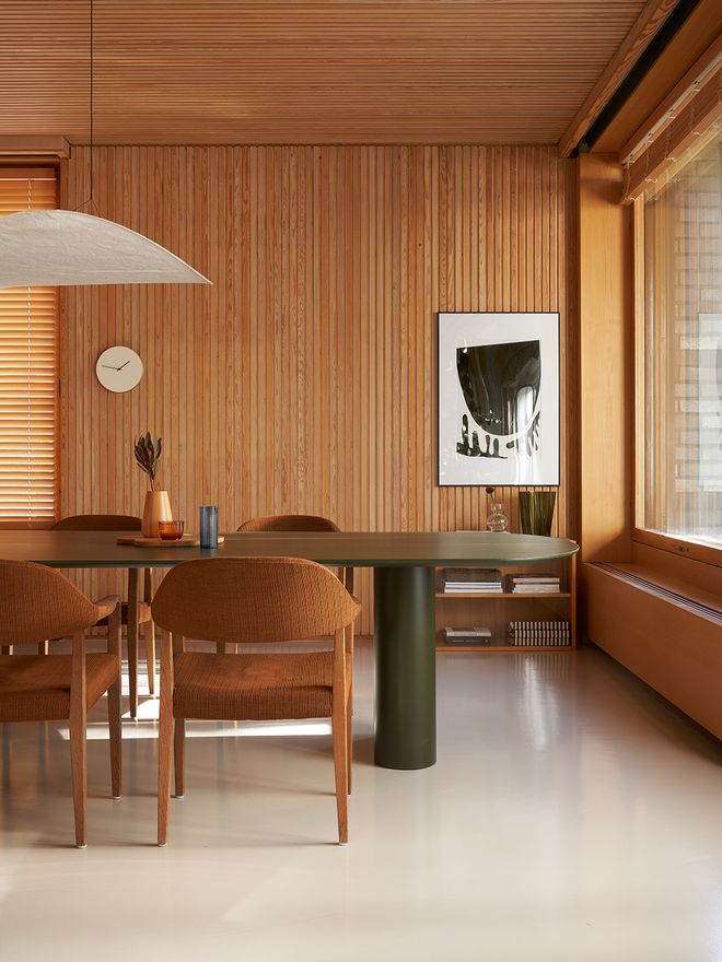 A dining room with a green table and vintage chairs