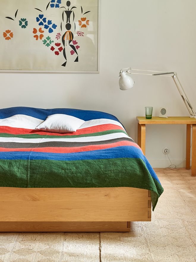 An image of a wooden bed with a colorful bedspread