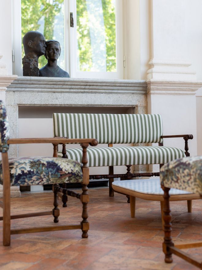 Reupholstered antique seating and a marble-topped coffee table in the Salone