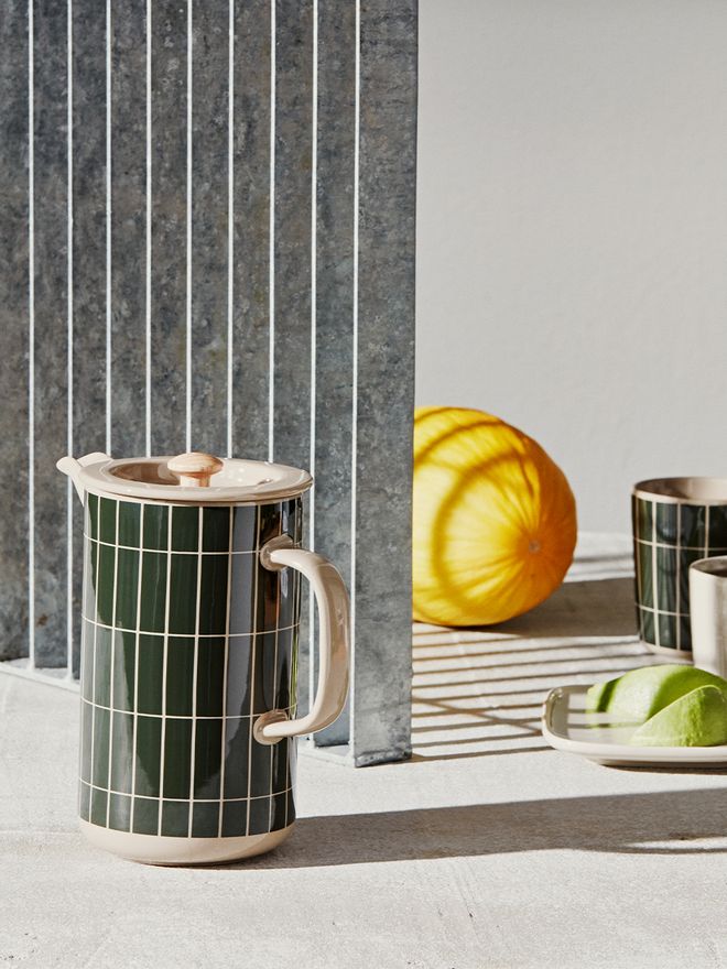 An image of Marimekko's Tiiliskivi press coffee maker and a matching coffee mug.