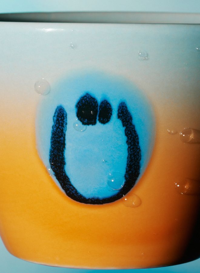 Close-up of a smiley face in a Frizbee Ceramics' cup