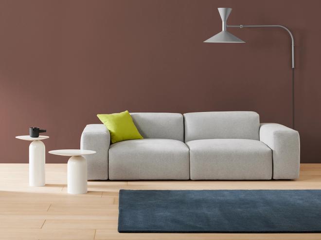 Basta's Cubi sofa in grey and two white Disco tables, all placed in a living room.