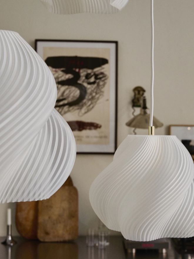 Close-up of two white Soft Serve lamps showcasing their softly swirling design in a warm interior setting