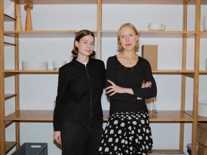 Iida Laiho ja Emma Ranne seisovat Kuoren puisten avohyllyjen edessä