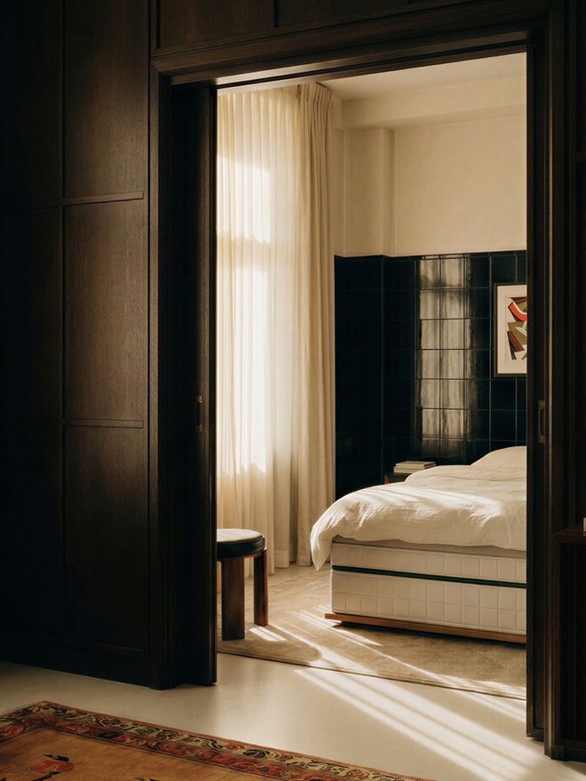 A photo taken from the doorway of a light-colored bedroom featuring a thick white mattress