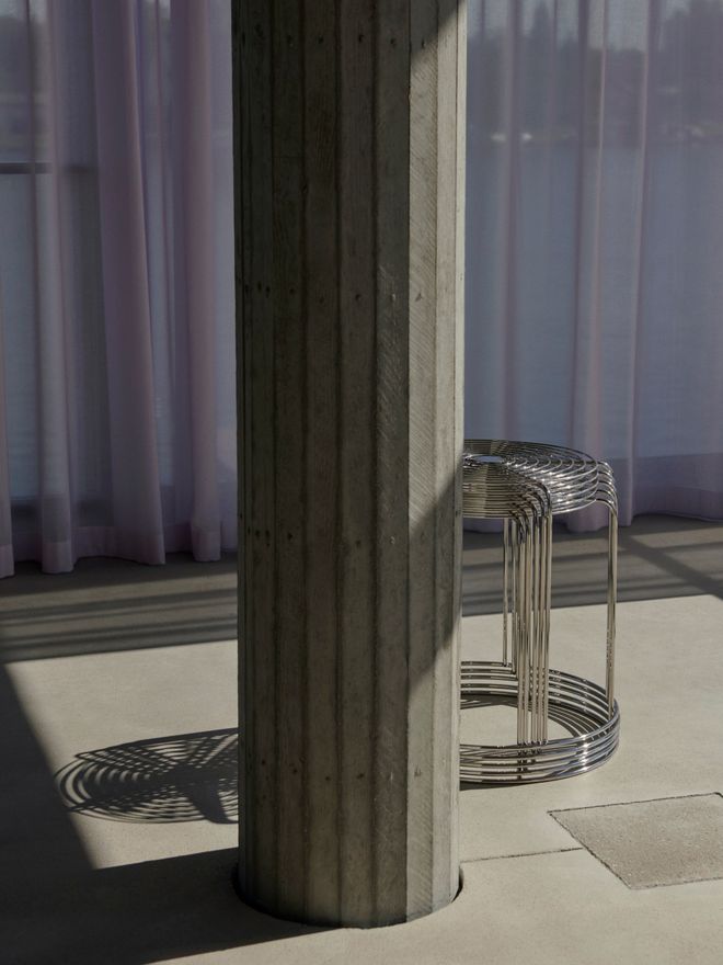 Wire stools stacked together and placed behind a concrete pillar