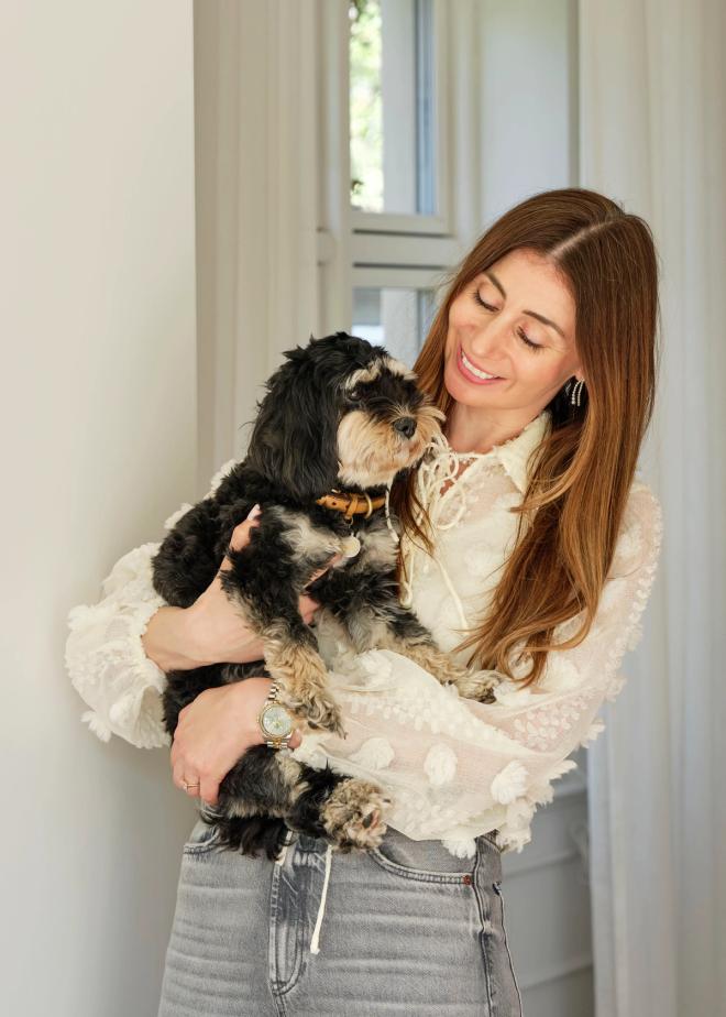 Nadia holding the family dog Nelly in her arms and smiling at her.