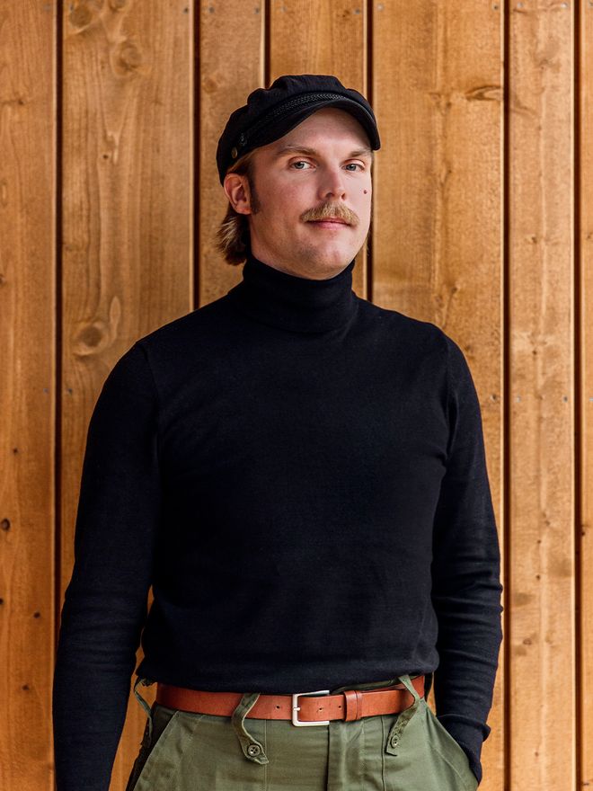 Designmyyjä Matias Rahkola katsoo kameraan, taustalla puuseinä.