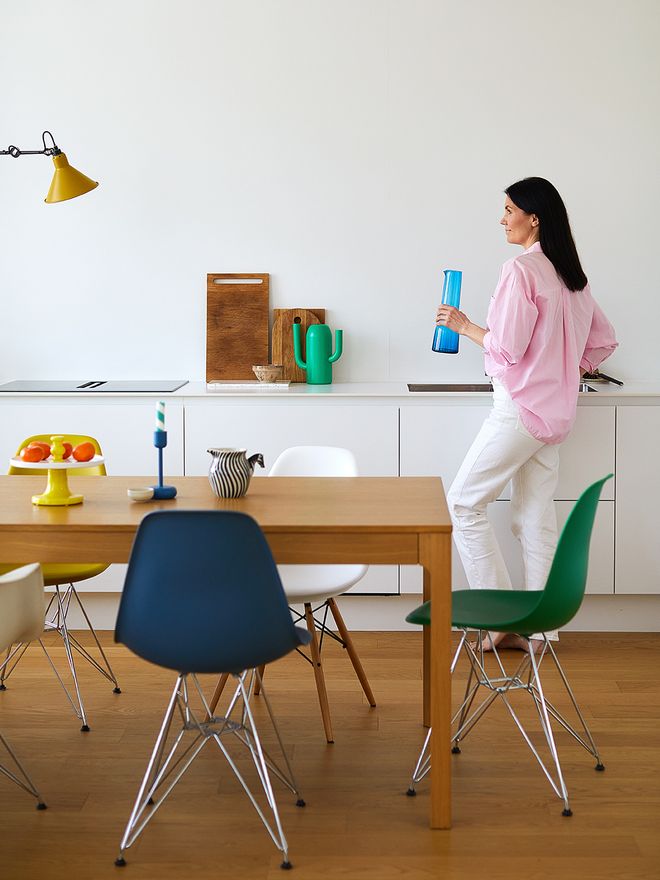 Maiju Kianta keittiössä, jossa on erilvärisiä Vitran Eames-tuoleja