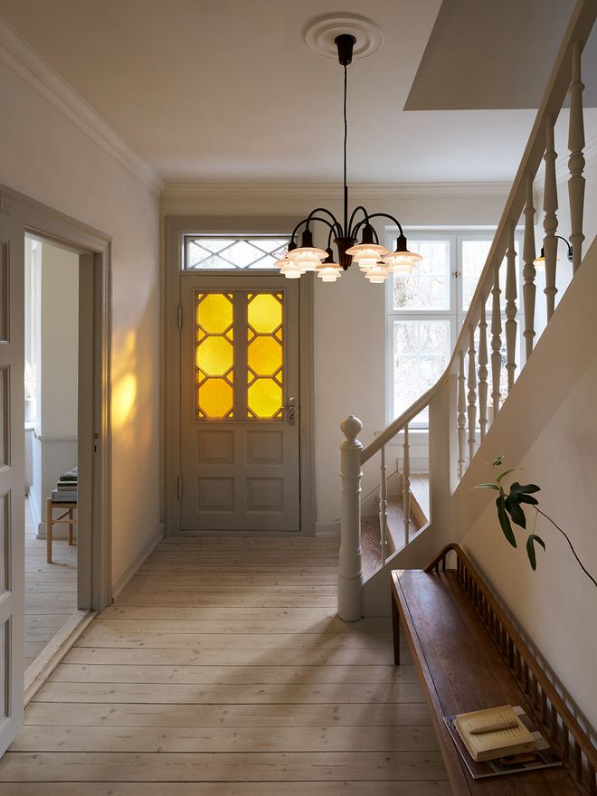 Louis Poulsen PH 1/1 Chandelier Centenary Edition with multiple curved aged brass arms and terracotta opal glass shades, hanging in an elegant residential entrance hall