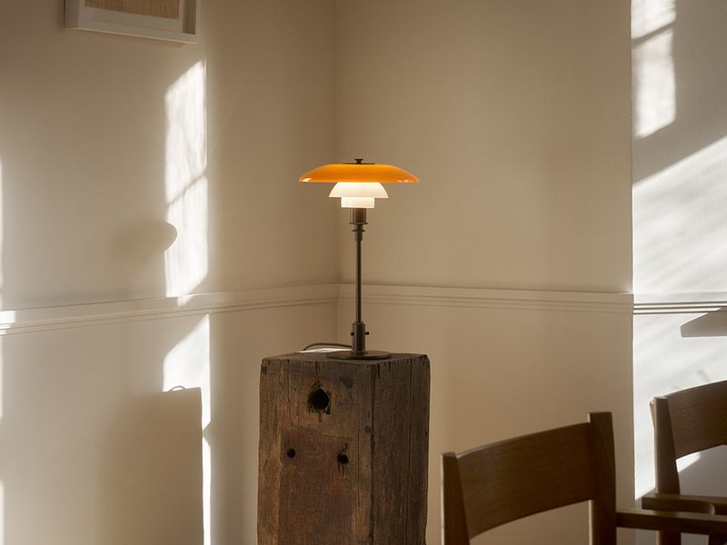 Louis Poulsen PH 3/2 Table Lamp Centenary Edition antiikkimessinkiä, meripihkan sävyinen ylävarjostin ja valkoiset opaalilasiset alavarjostimet, esillä valoisassa skandinaavisessa sisustuksessa