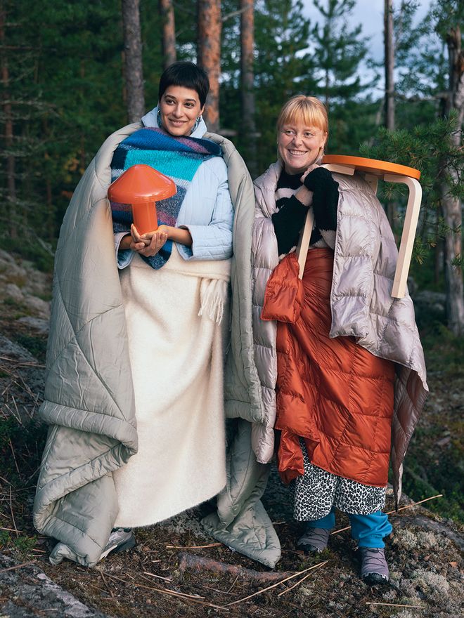 Two persons in the Finnish forest with furniture and blankets.