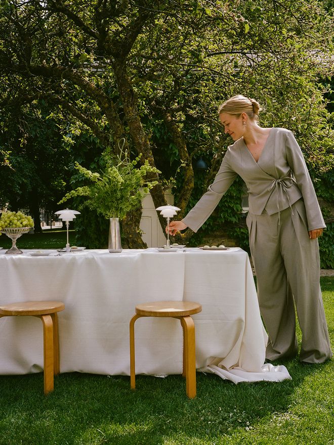 Klara Marie Jespersen outdoors next to a table setting, holding a Louis Poulsen lamp