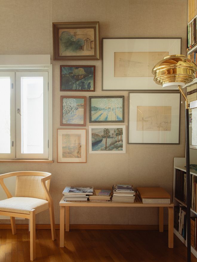 Paintings by Alvar Aalto from his youth displayed on the living room wall at Villa Skeppet, alongside an Artek A808 floor lamp with a brass shade