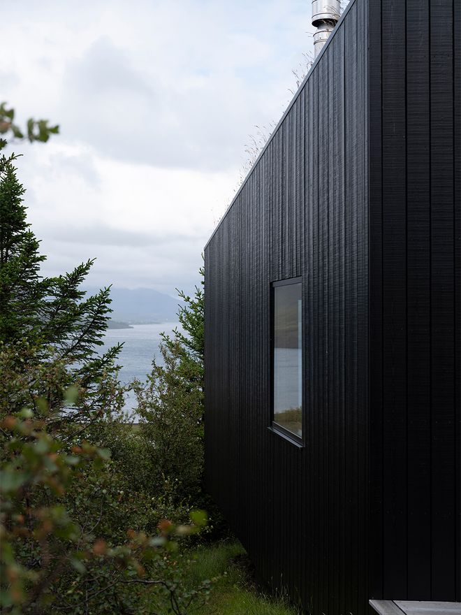 An image of the Holiday home by Þingvallavatn by KRADS architects: a leisure home located in Iceland in the middle of a picturesque scenery. This image features the buildings black facade.