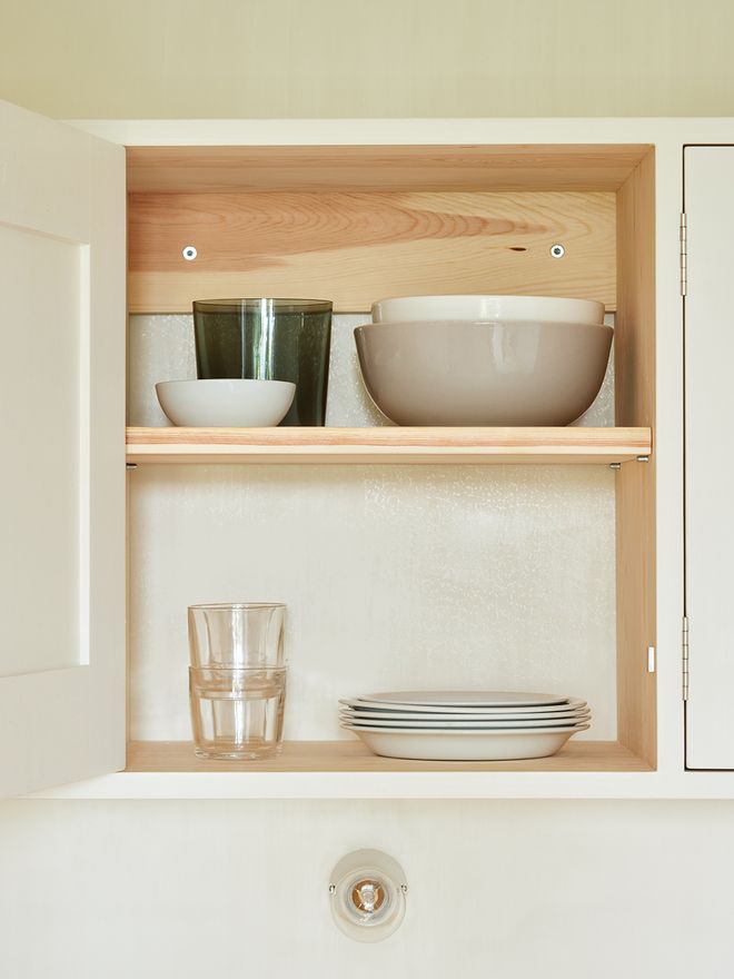 An open kitchen cabinet with tableware on the shelves