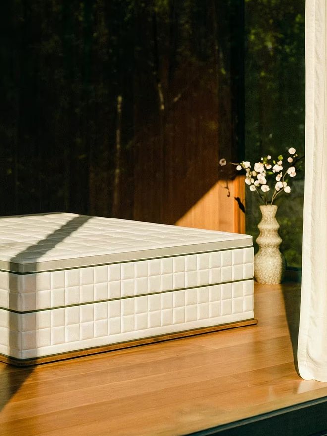 A thick Muun MK2 Continental mattress on a light-colored bed frame in a bright bedroom