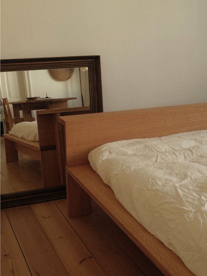 A photo of the headboard and a mirror reflecting the surrounding, calmly decorated room